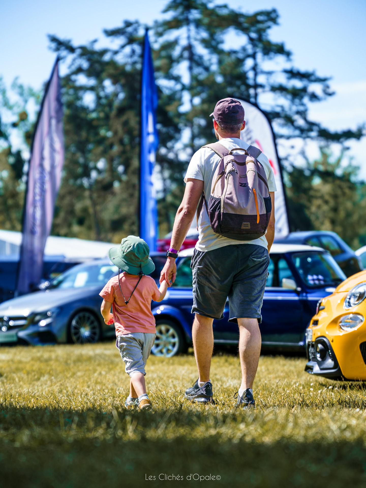 Famille avec enfant lors d'une exposition de voitures anciennes en plein air.
