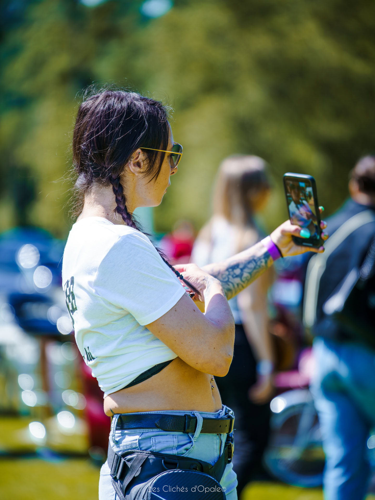 Jeune femme avec lunettes, tenant son téléphone pour capturer un moment lors d'une sortie en nature.