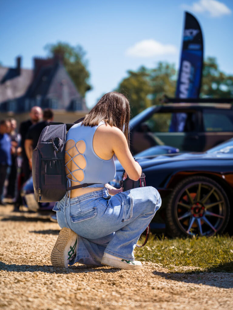 Vitrine de voiture sportive lors d'un événement en plein air, avec spectateurs et ambiance dynamique.