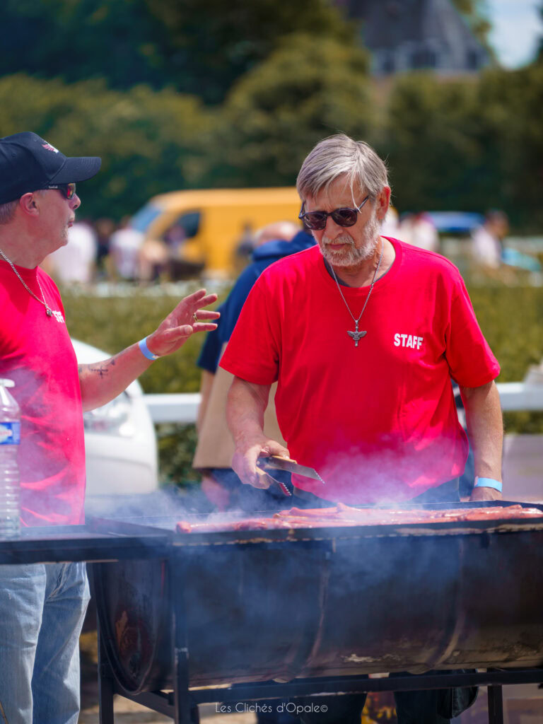 Femme et homme en t-shirts rouges, cuisson sur un barbecue en extérieur.