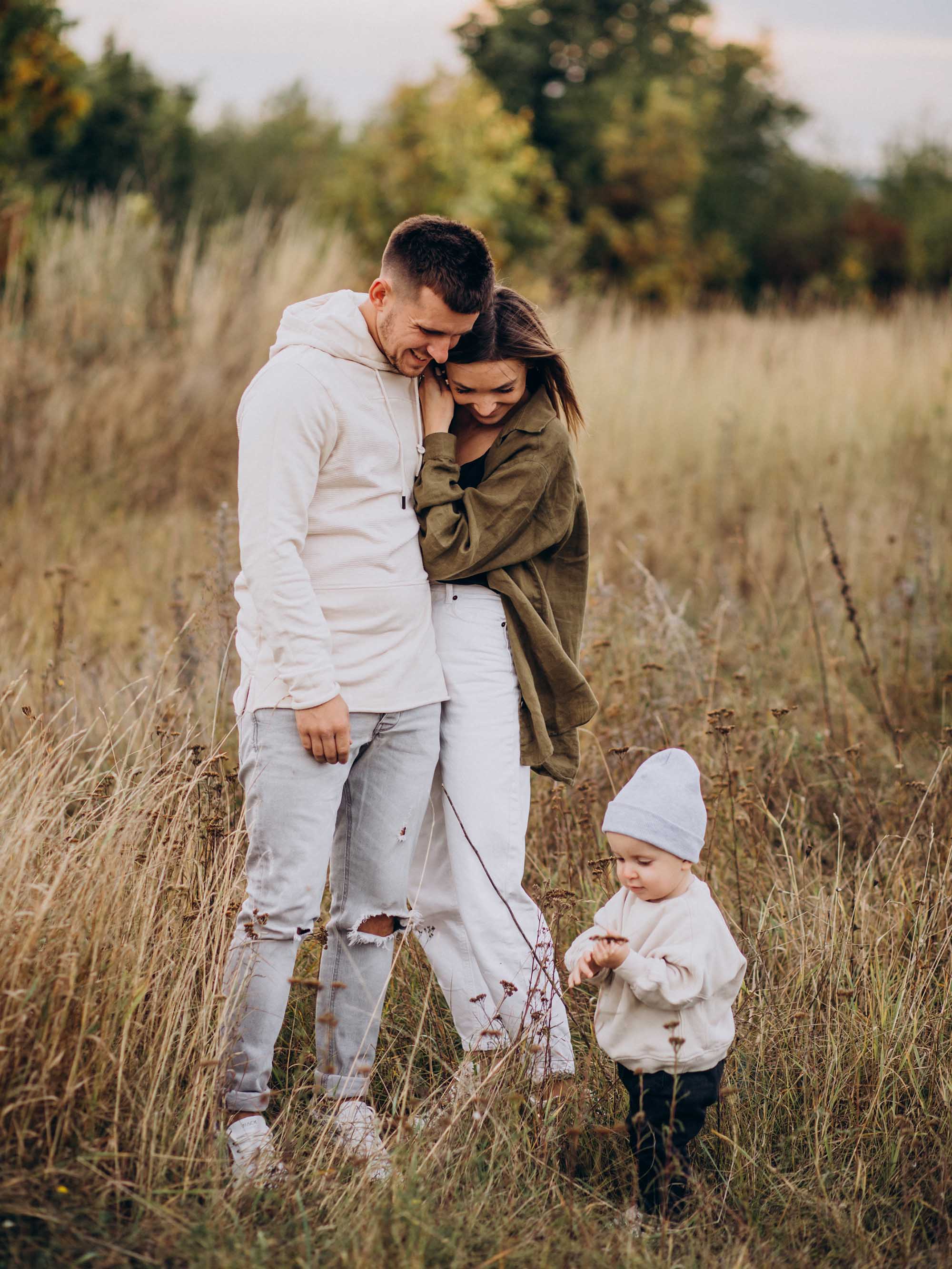Famille heureuse avec un enfant dans un champ d'automne, nature et détente.